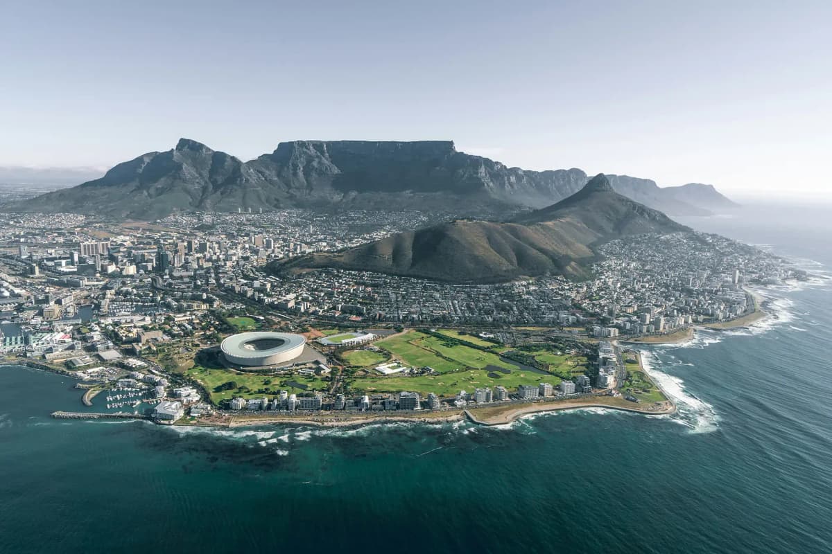 Panorama mozzafiato di Città del Capo, con la montagna della Tavola che sovrasta la città e l’Olympic Stadium visibile lungo la costa sudafricana.
