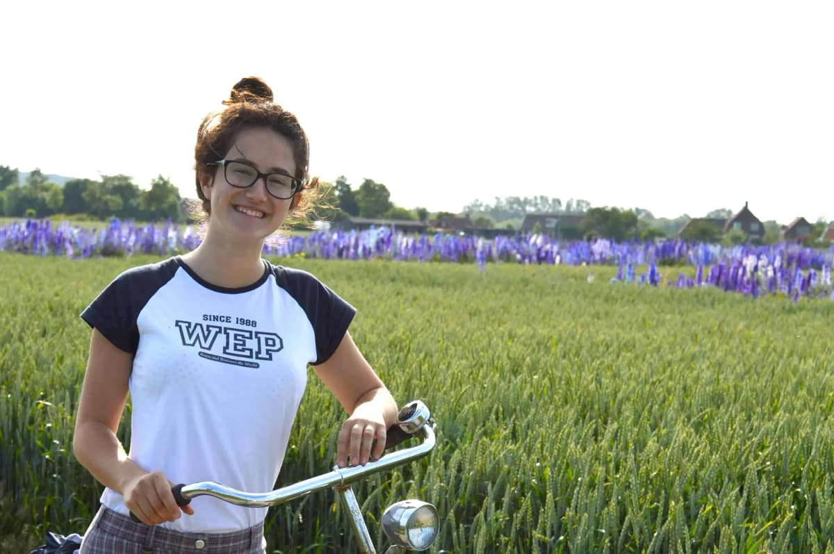 Studentessa con bicicletta immersa nella natura nei Paesi Bassi, simbolo della vita quotidiana e della libertà durante l’anno all’estero.