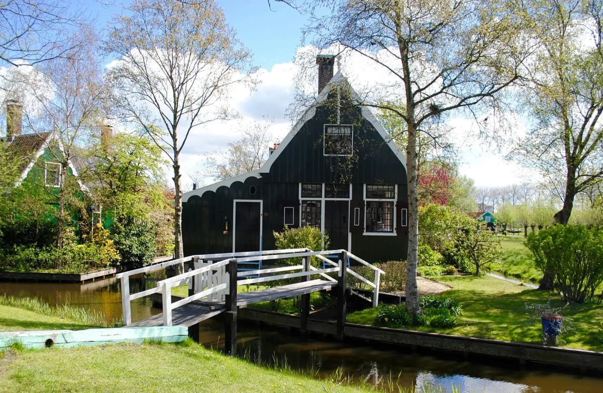 Casa tradizionale olandese circondata dal verde e attraversata da un canale, tipico paesaggio dei Paesi Bassi durante l’anno all’estero.