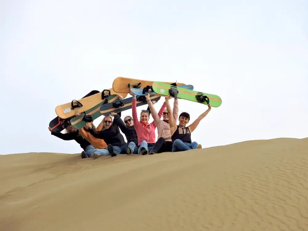 Gruppo di studenti su una duna di sabbia in Cile con sandboard sollevate, durante un anno all’estero tra sport, amicizia e avventura.