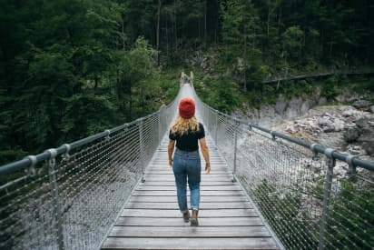 Studentessa che attraversa un ponte immerso nella natura, simbolo di crescita personale e scoperta durante un anno all’estero Canada.