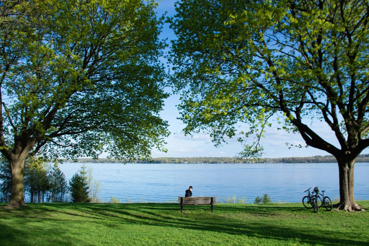 Studente seduto su una panchina davanti a un lago durante un Anno scolastico all’estero in Canada, immerso nella natura