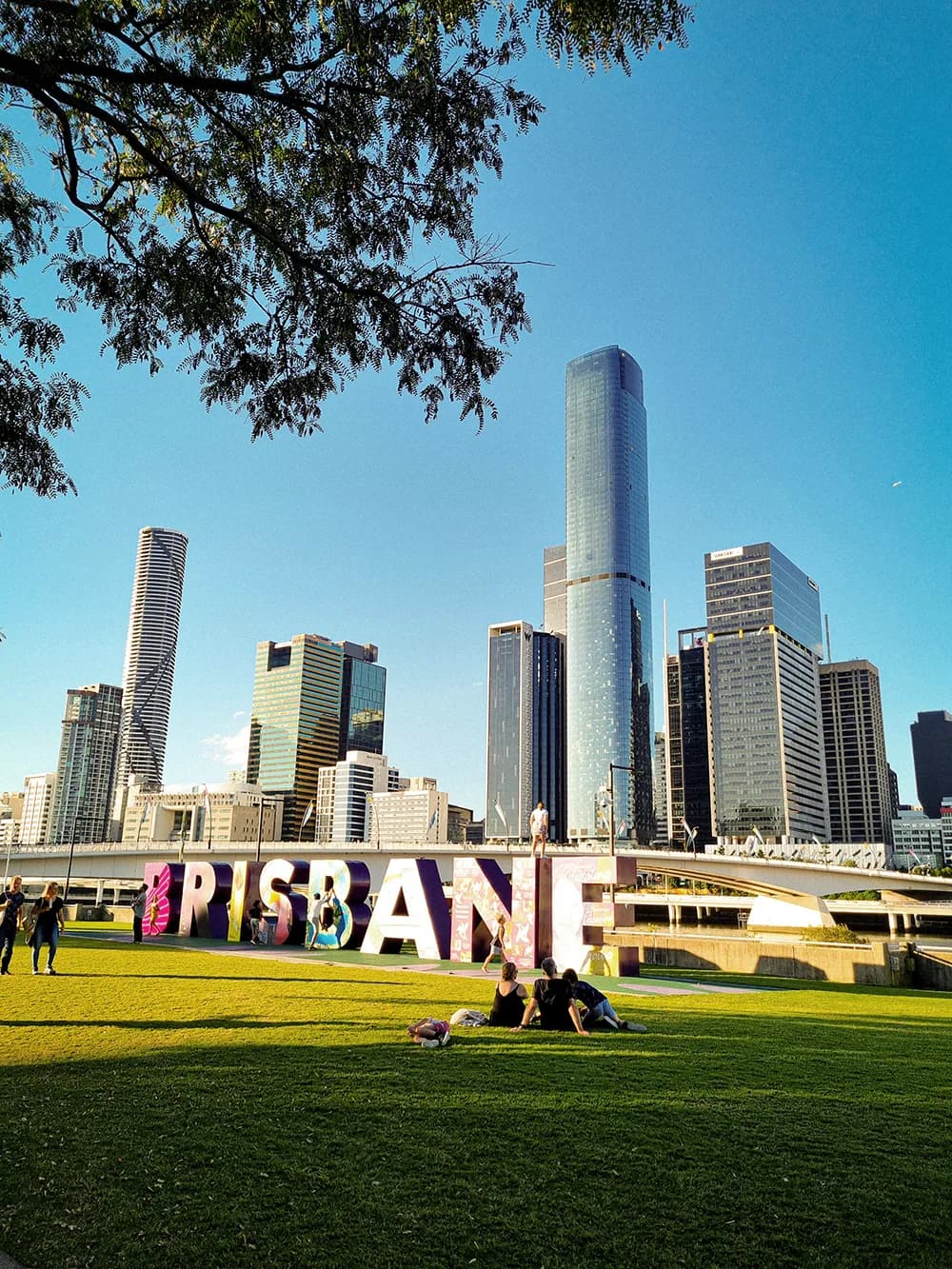 Persone si rilassano in un parco davanti allo skyline di Brisbane durante un soggiorno linguistico in Australia