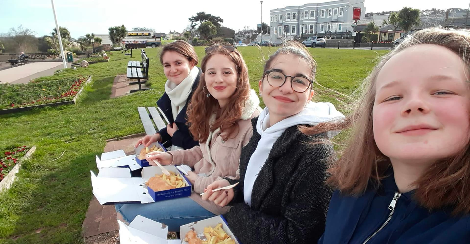 Studenti seduti all’aperto mentre mangiano insieme durante un Anno scolastico all’estero nel Regno Unito, vivendo momenti di socialità.