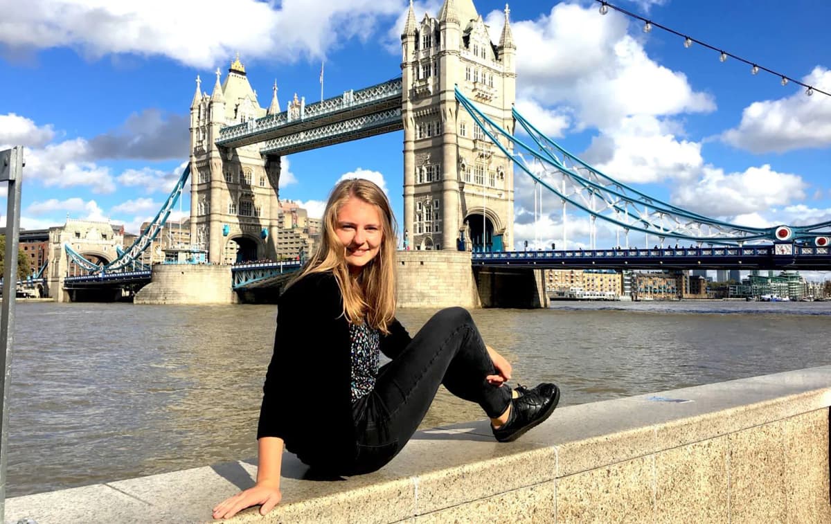 Studentessa seduta vicino al Tower Bridge a Londra durante un anno scolastico all’estero nel Regno Unito.