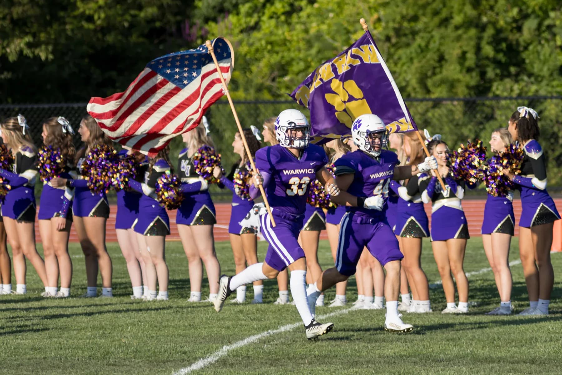 Squadra di football e cheerleader durante una partita scolastica, esempio di sport e vita studentesca nel sistema scolastico americano durante l’anno all’estero in USA.