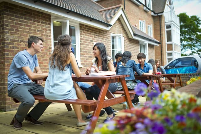 Studenti che socializzano all’aperto durante una vacanza studio in Inghilterra, godendo di un momento di relax insieme in un ambiente stimolante